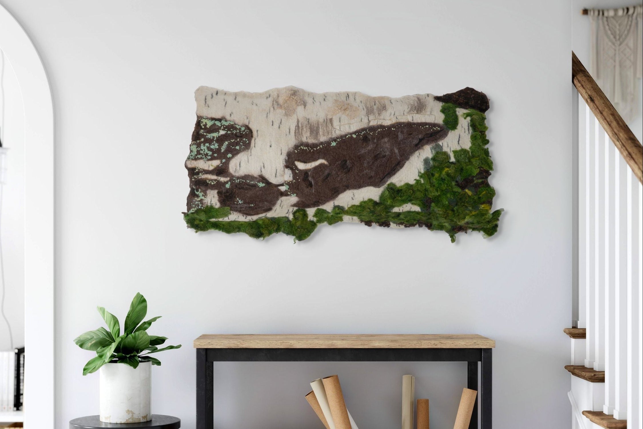 Moss wall art on a white wall with a console table and plant in the foreground